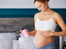 Young pregnant women applying cream on her belly